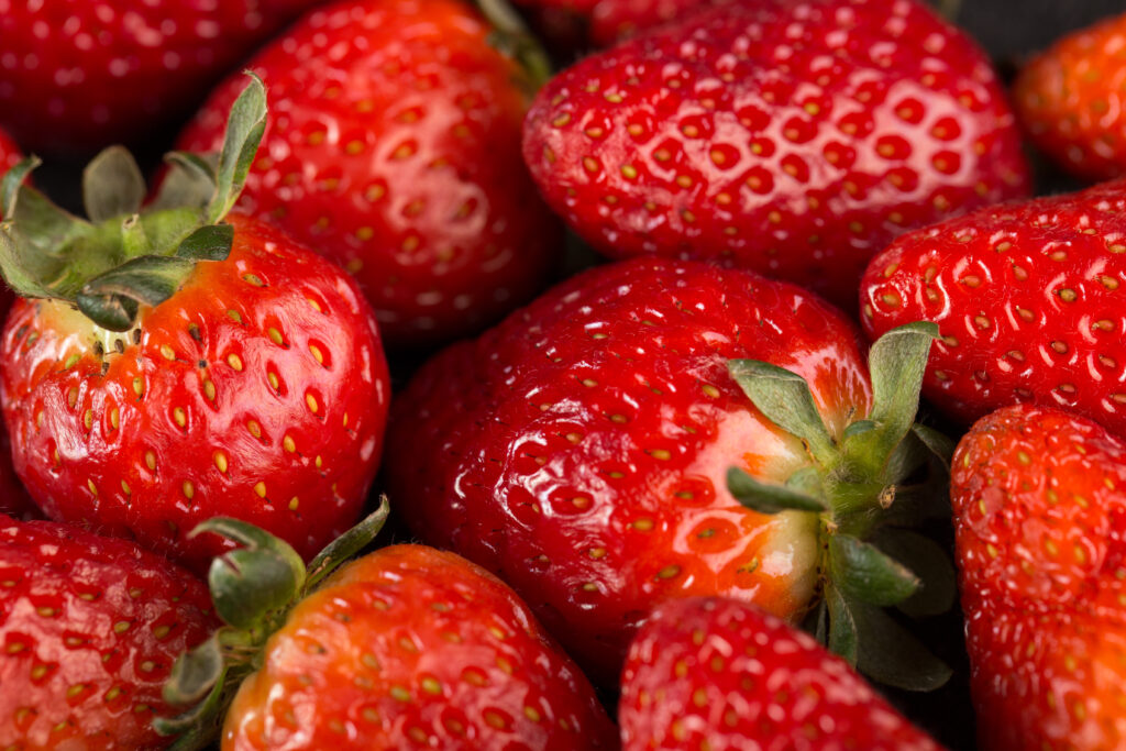 yummy-strawberries-red-mellow-ripe-with-green-leafs-dark-desk